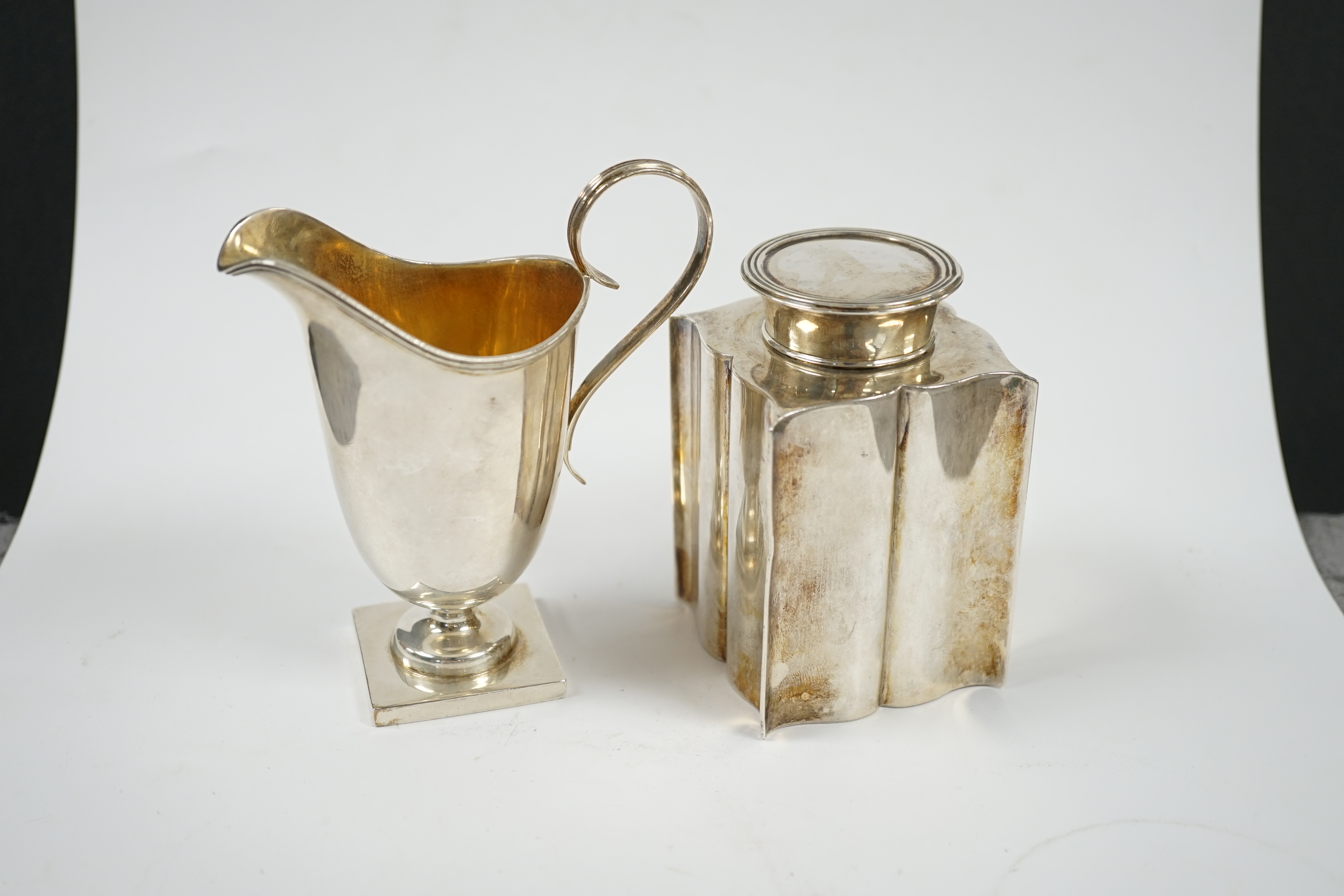 An Edwardian silver ‘bats wing’ tea caddy, Birmingham, 1906, 95mm and a George V silver cream jug. Condition - fair